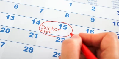 Hand circling doctor appointment on calendar.